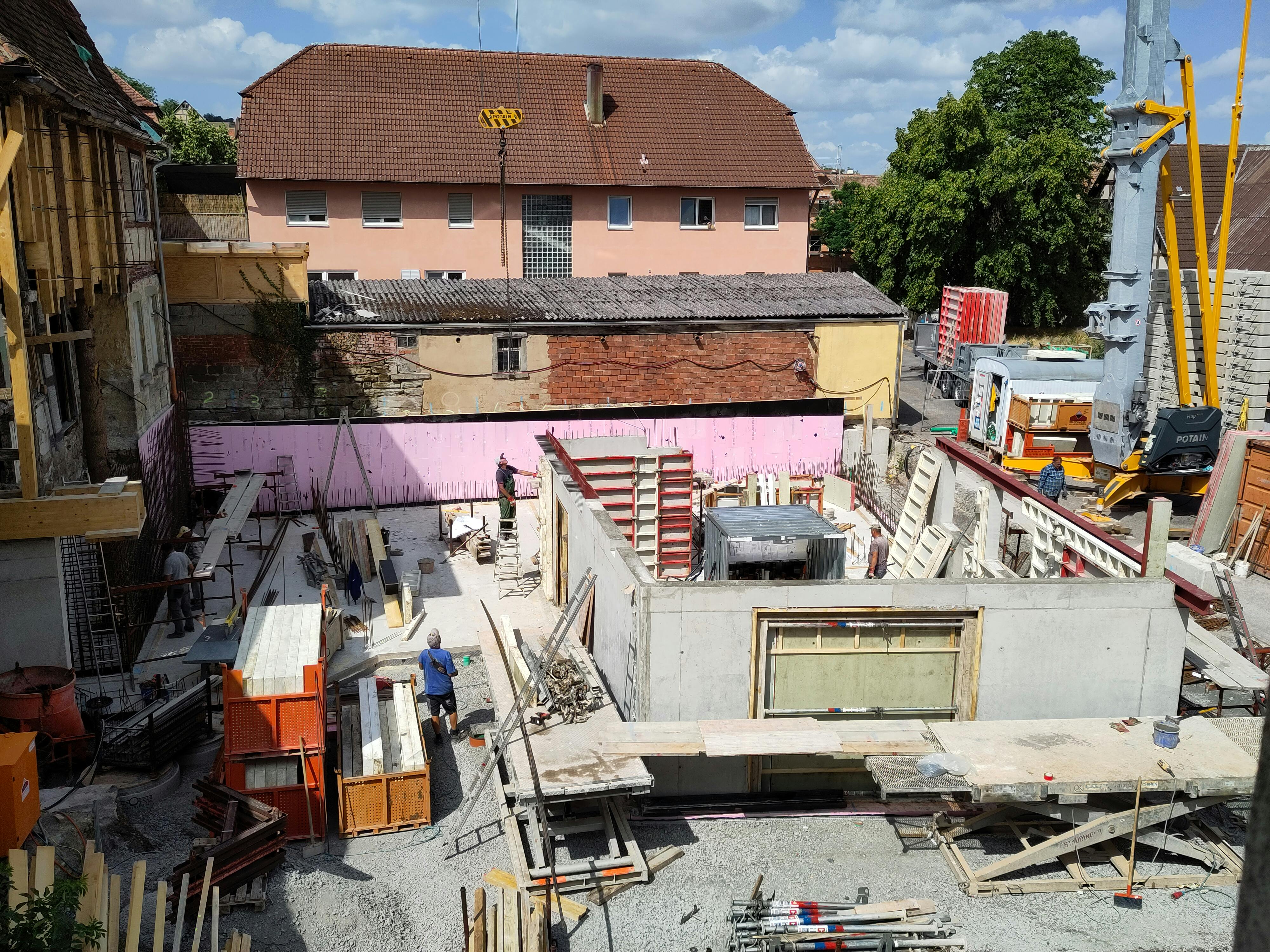 Hierzu werden alle auf Zug belasteten Bauteile durch Bewehrungen aus Stahl verstärkt, die durch Draht miteinander verbunden sind. Alle Wände werden anschließend geschalt. Die Schalung dient dem Beton primär als Form und leitet dabei die entstehenden Kräfte in die Unterkonstruktion ab. Bereits am nächsten Tag kann die Schalung wieder entfernt werden und das Untergeschoss nimmt allmählich Konturen an. Das beiden Zugangstore zum Mostereibereich sind erkennbar ebenso wie die Verbindung zum späteren Flur.